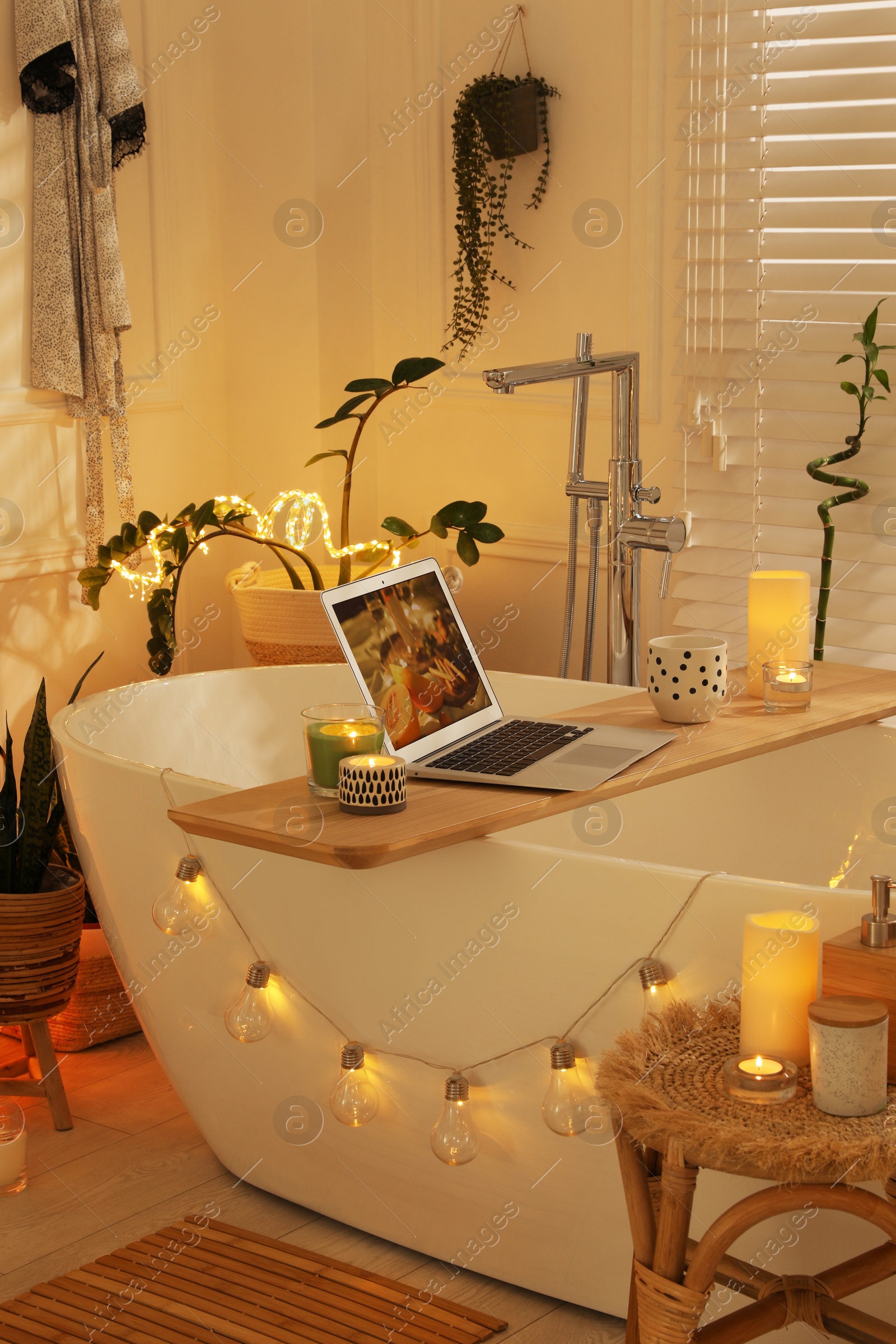 Photo of Stylish bathroom interior with green houseplants and string lights. Idea for design