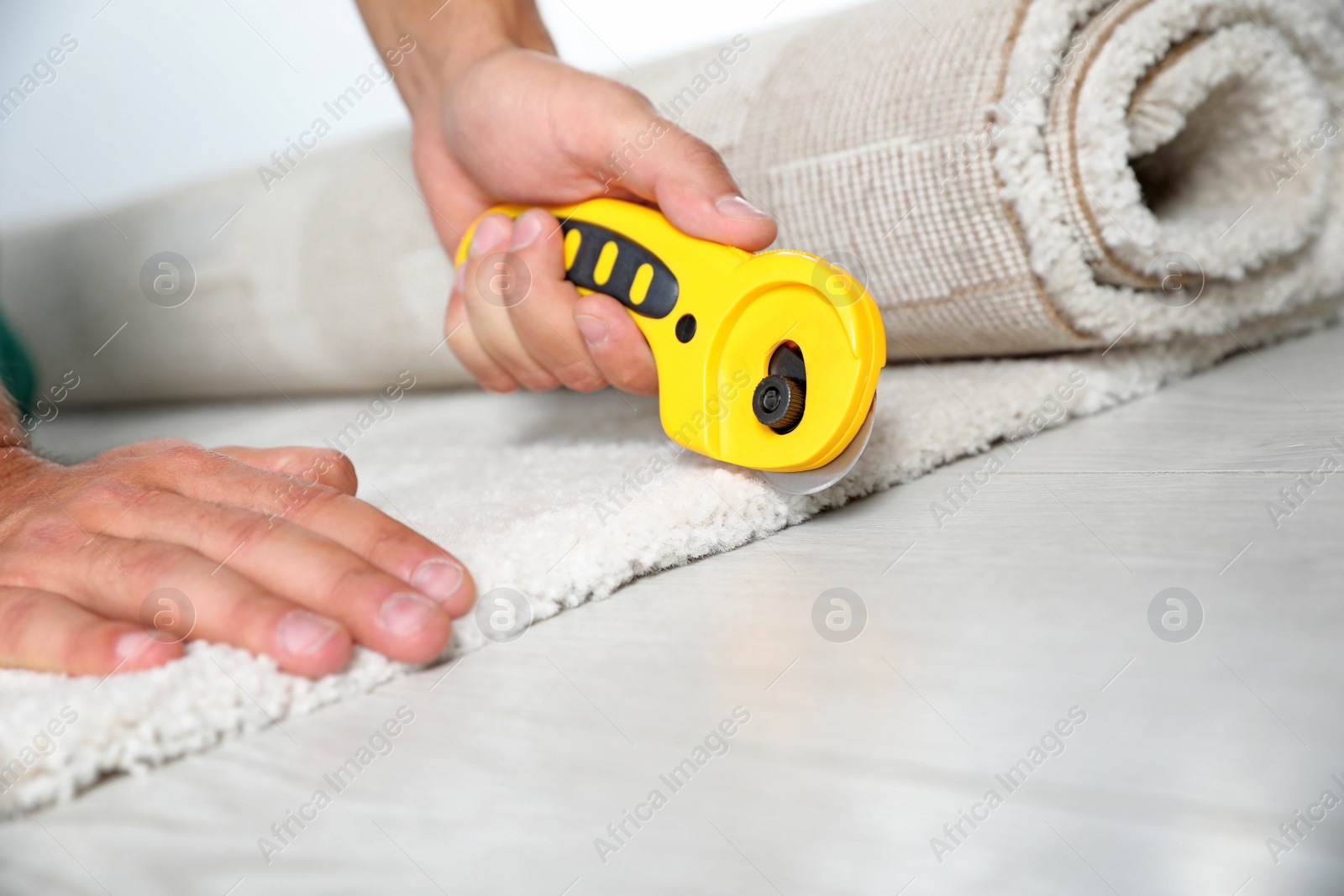 Photo of Man cutting new carpet flooring indoors, closeup. Space for text