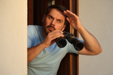 Concept of private life. Curious man with binoculars spying on neighbours outdoors