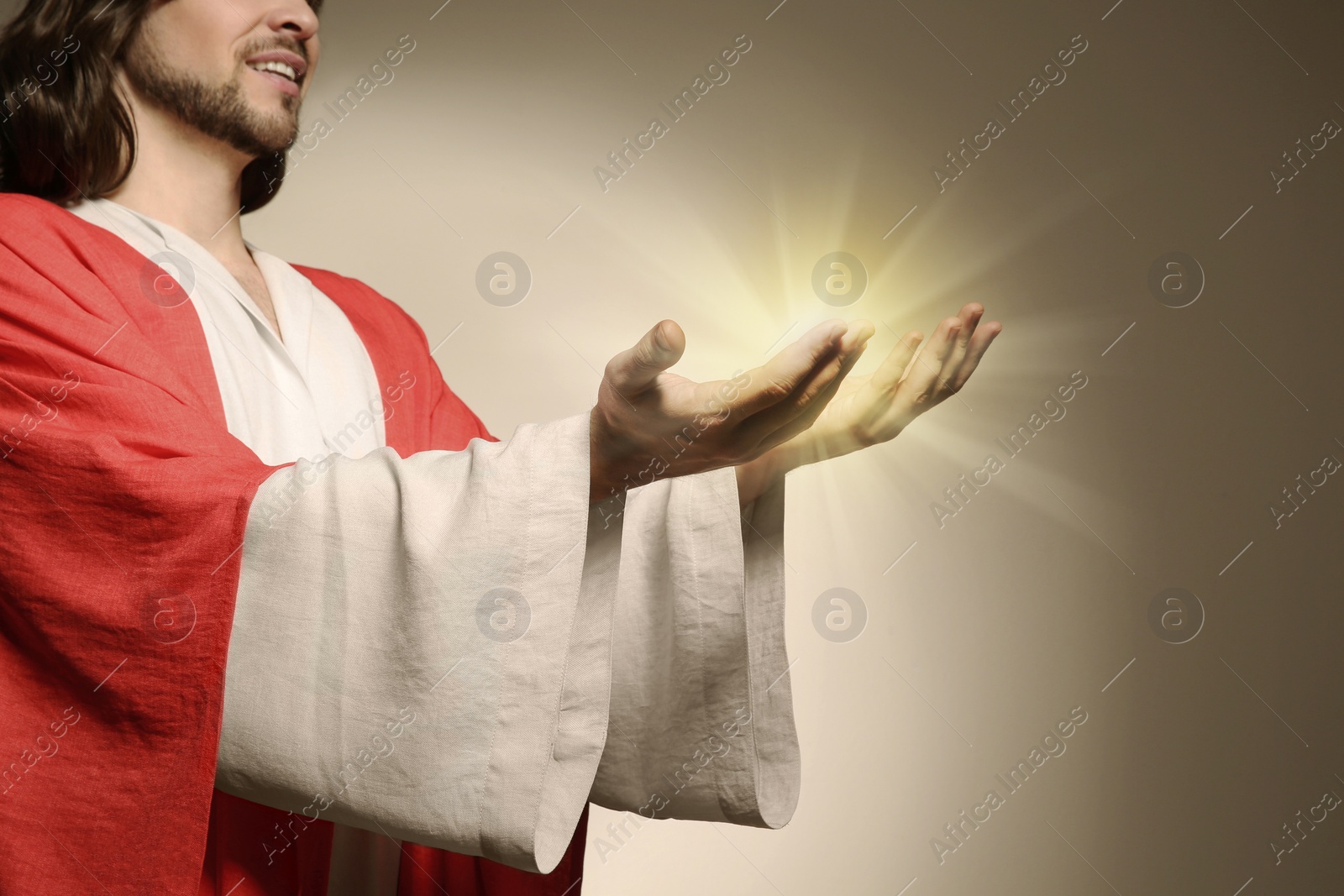 Image of Jesus Christ on beige background, closeup. Miraculous light in hands