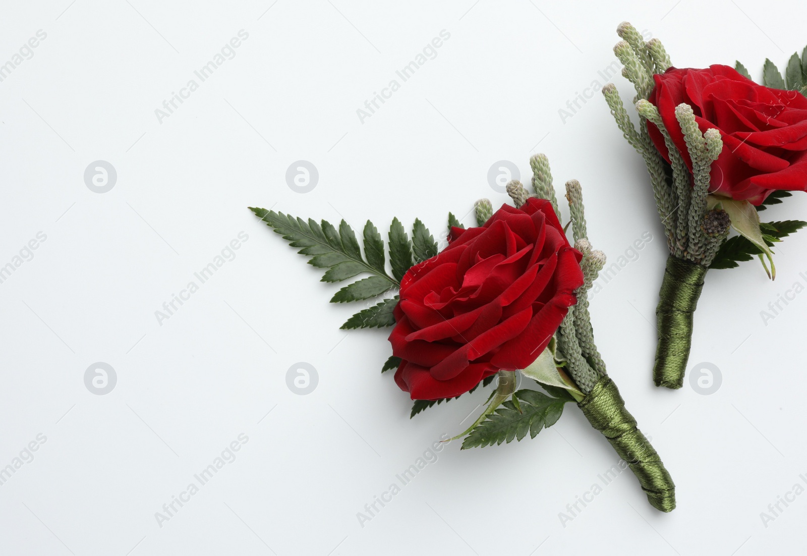 Photo of Two stylish red boutonnieres on white background, top view. Space for text