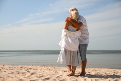 Photo of Mature couple spending time together on sea beach, back view