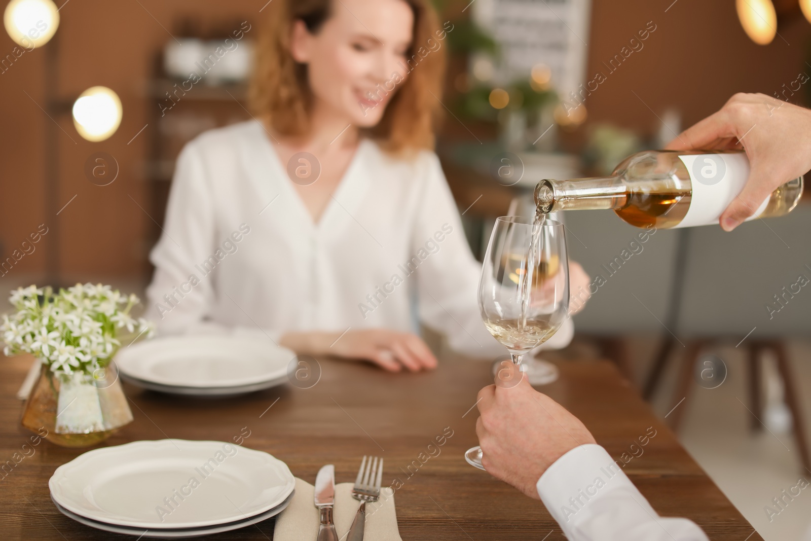 Photo of Waiter pouring wine into glass for client at restaurant