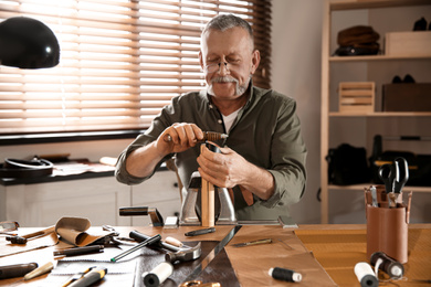 Photo of Man burnishing edges of leather belt in workshop