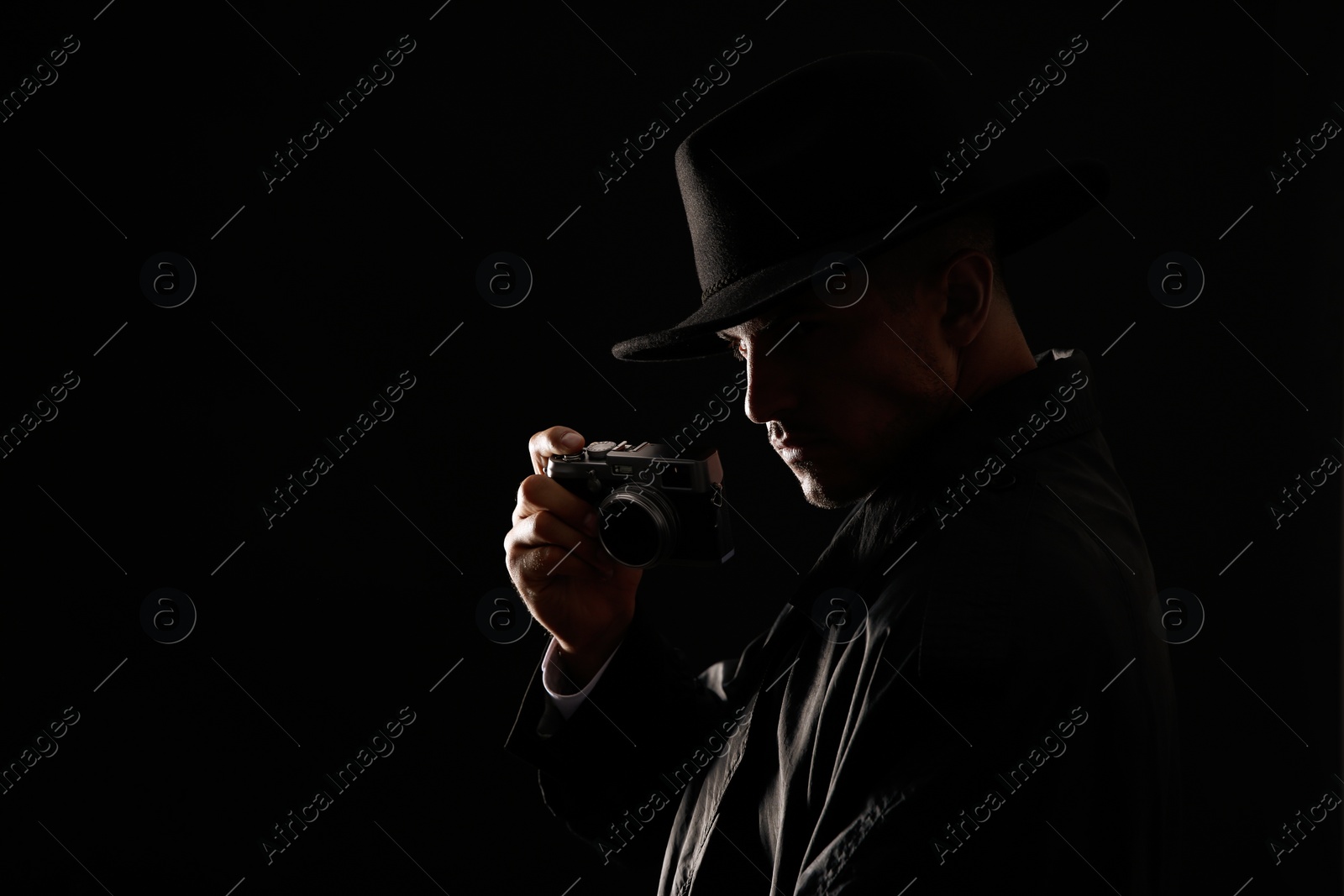 Photo of Old fashioned detective with camera on dark background. Space for text