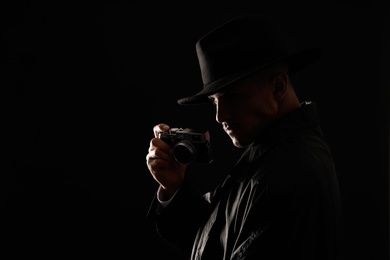 Photo of Old fashioned detective with camera on dark background. Space for text