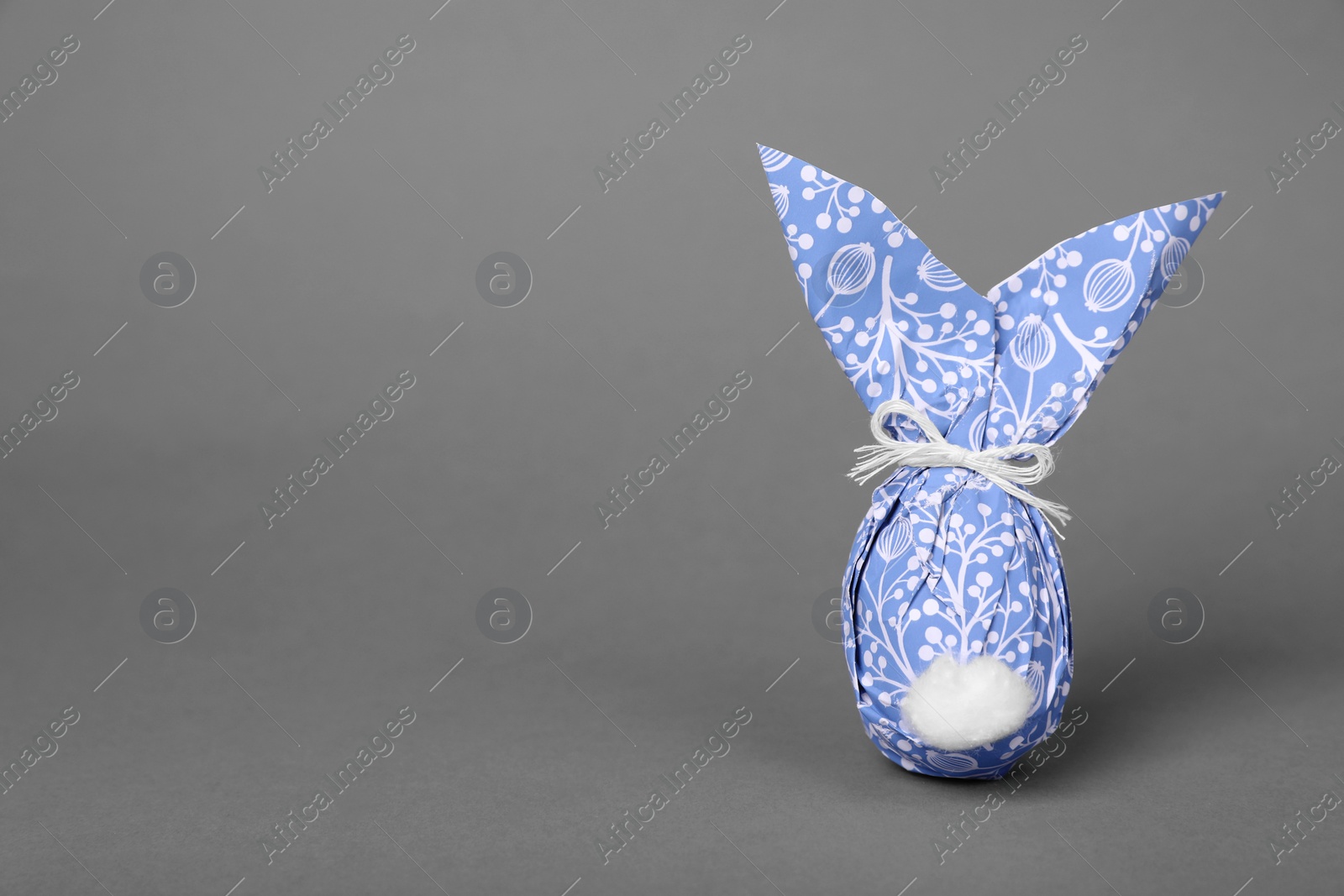 Photo of Easter bunny made of wrapping paper and egg on grey background. Space for text