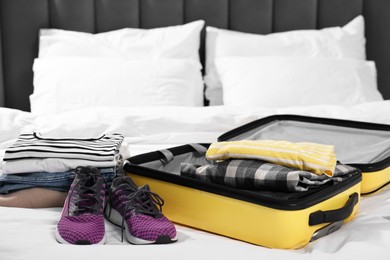 Photo of Clothes, shoes and suitcase on bed indoors. Packing for travel