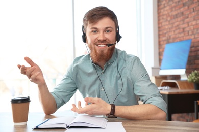 Young man with headset looking at camera and using video chat in home office