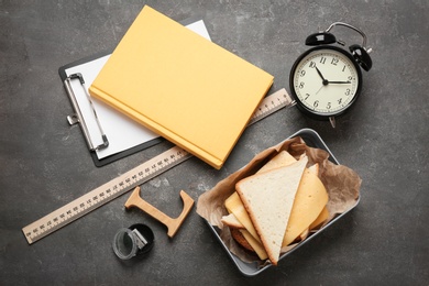 Flat lay composition with lunch box, sandwich and stationery on grey background