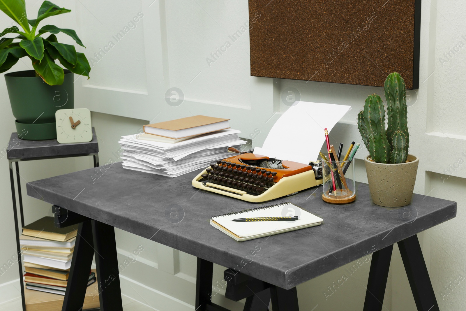 Photo of Typewriter and stack of papers on dark table in room. Writer's workplace