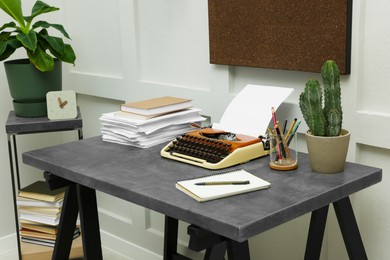 Photo of Typewriter and stack of papers on dark table in room. Writer's workplace