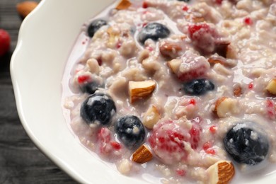 Photo of Tasty oatmeal porridge with toppings on table, closeup