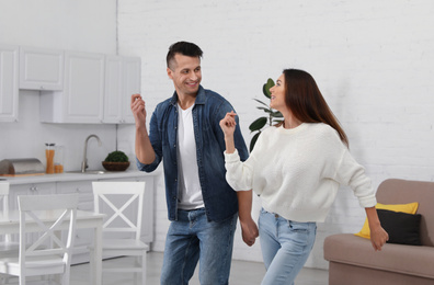 Photo of Happy couple dancing in kitchen at home