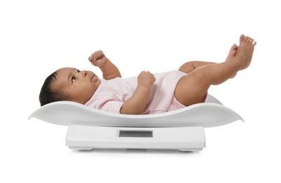 African-American baby lying on scales against white background