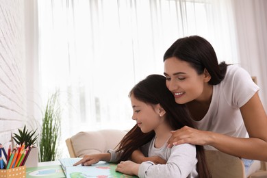 Photo of Happy mother and daughter reading book together at home. Single parenting