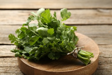 Photo of Bunch of fresh coriander on wooden table, closeup