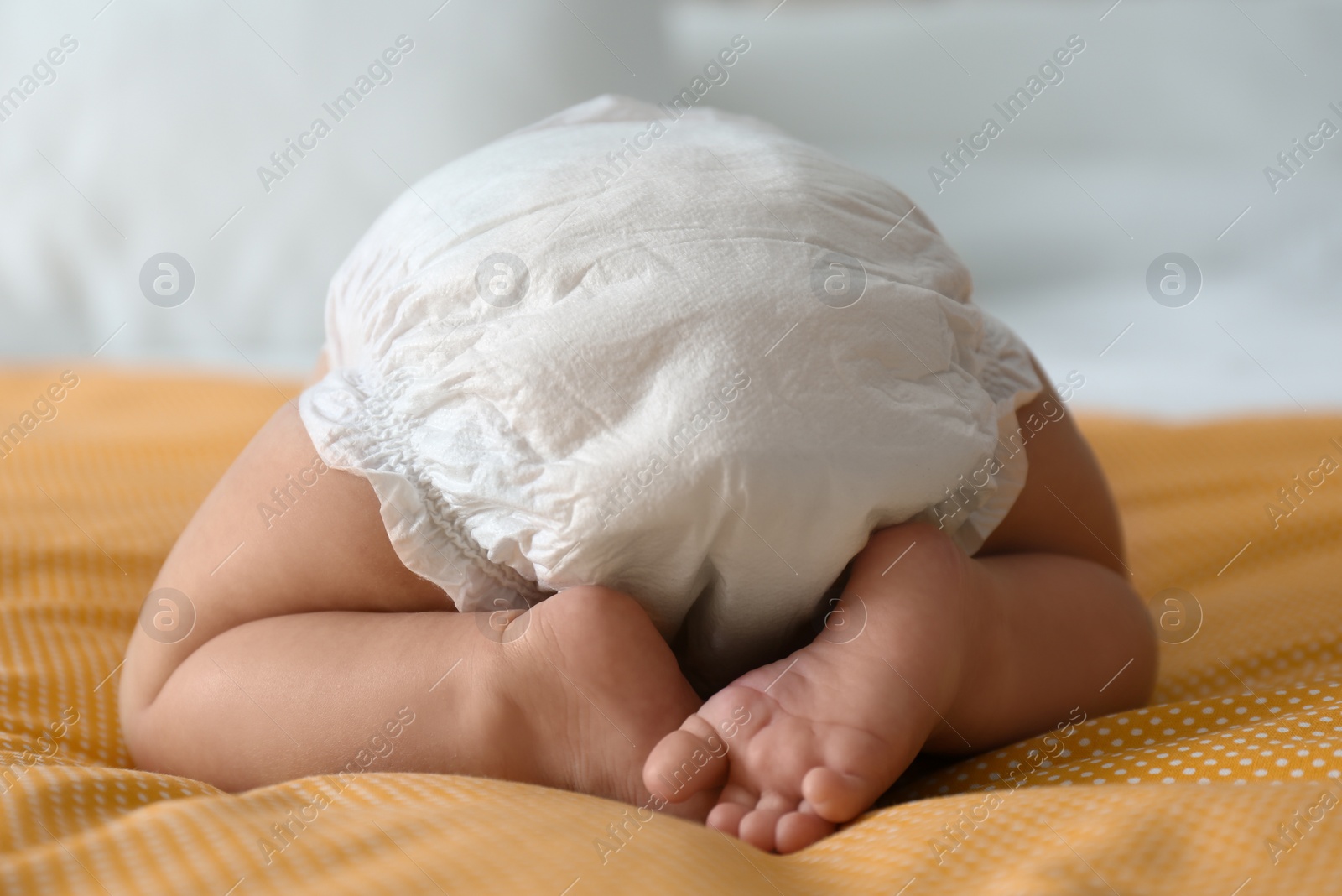 Photo of Cute little baby in diaper on yellow blanket