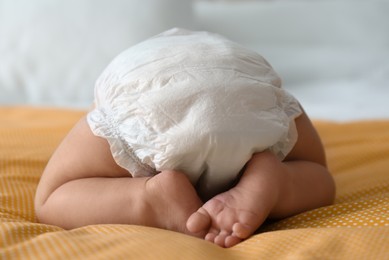 Photo of Cute little baby in diaper on yellow blanket