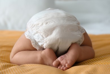 Cute little baby in diaper on yellow blanket