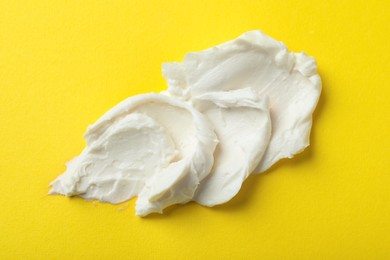 Photo of Smear of delicious cream cheese on yellow background, top view