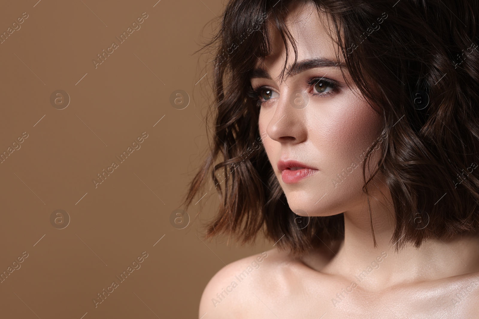 Photo of Beautiful young woman with wavy hairstyle on brown background. Space for text
