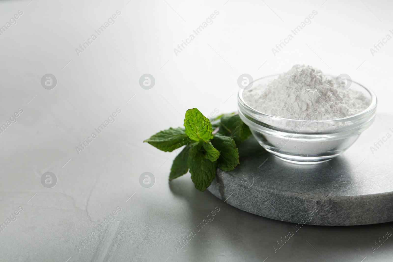 Photo of Tooth powder and mint on grey table, closeup. Space for text