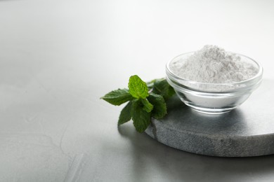 Tooth powder and mint on grey table, closeup. Space for text