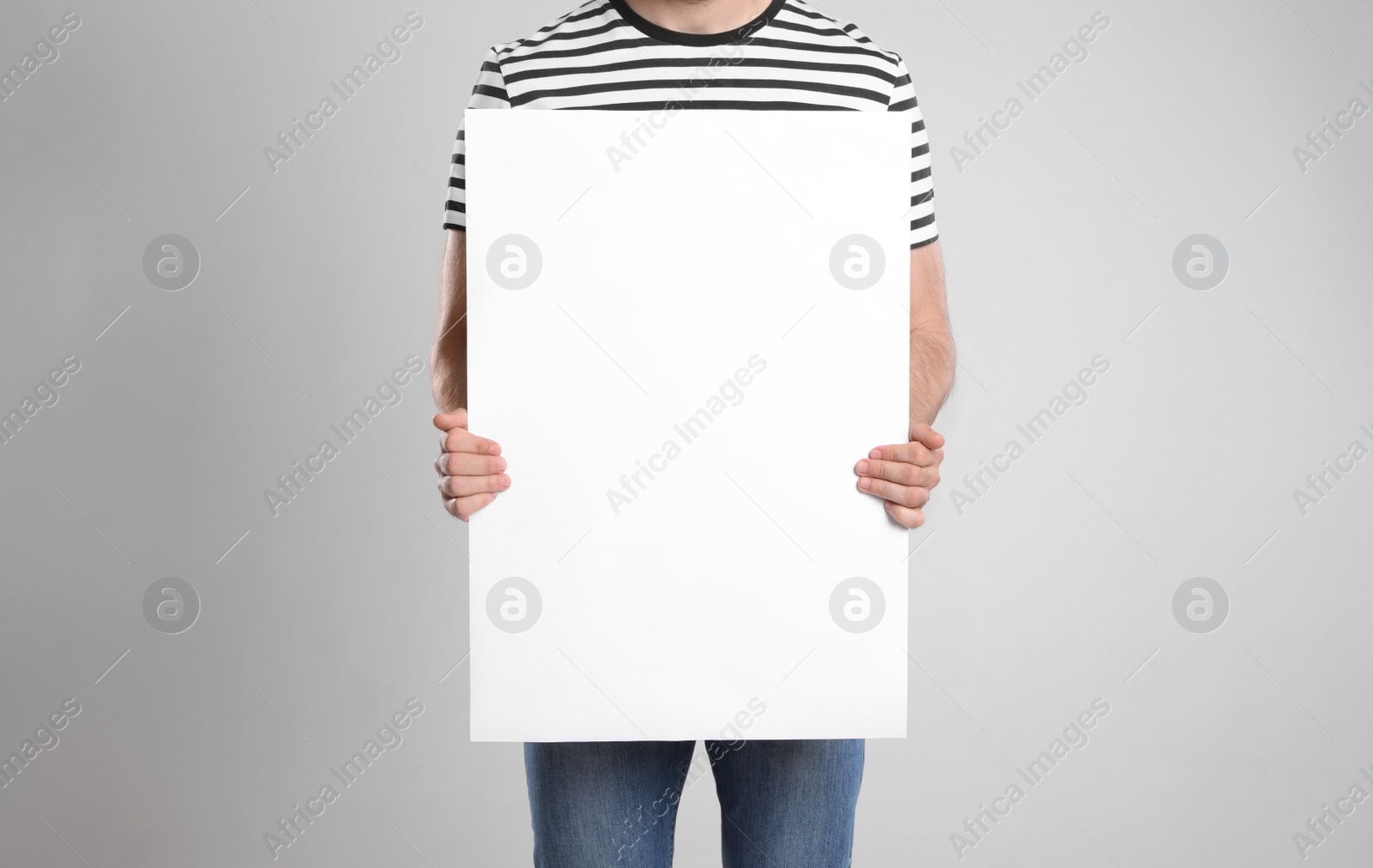 Photo of Man holding blank poster on light grey background, closeup