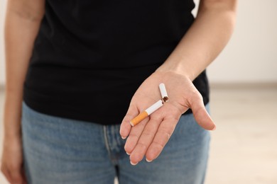 Photo of Stop smoking concept. Woman holding broken cigarette on beige background, closeup