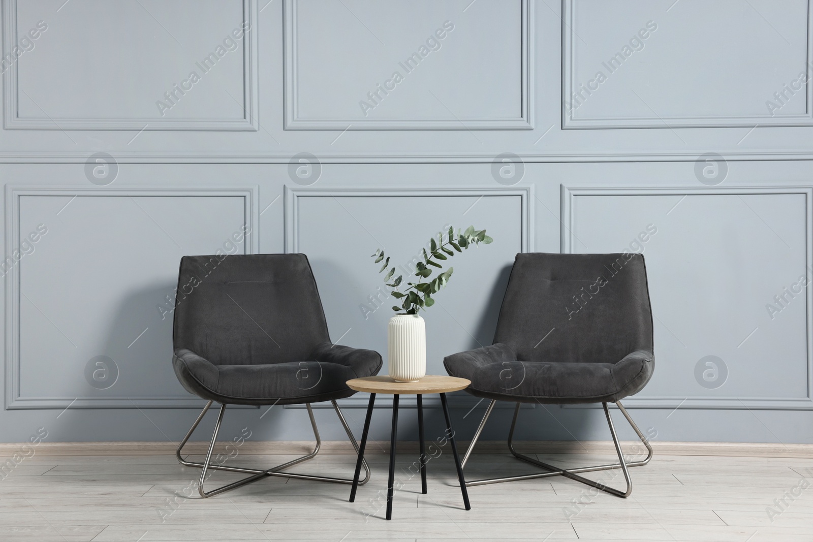 Photo of Comfortable armchairs, side table and eucalyptus indoors