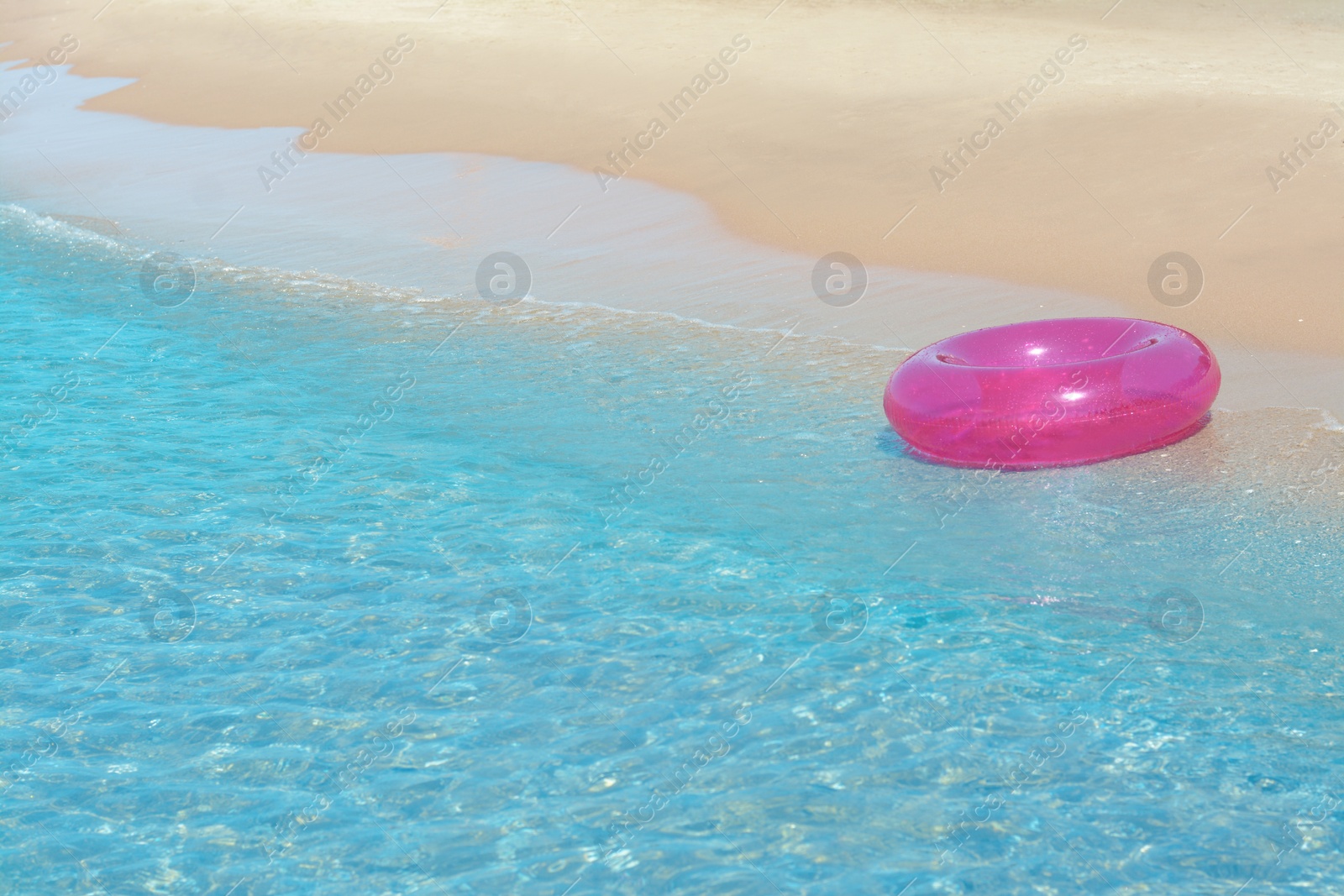 Photo of Bright inflatable ring on sandy beach near sea. Space for text