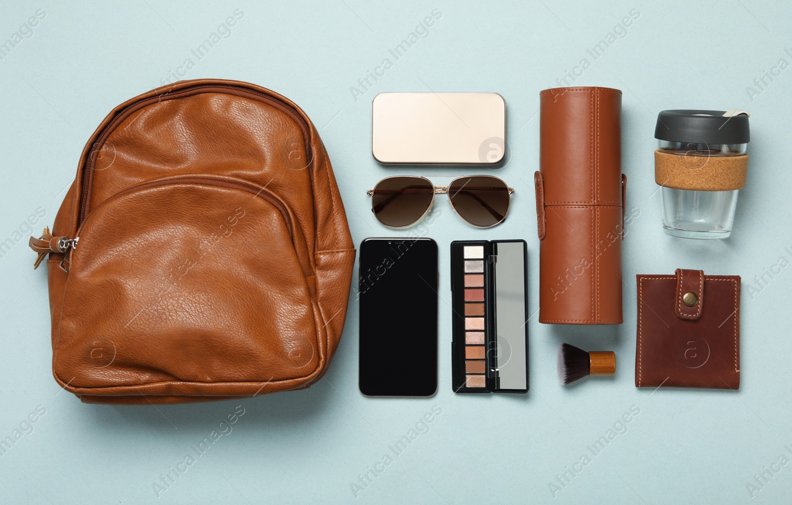 Photo of Stylish urban backpack with different items on light background, flat lay