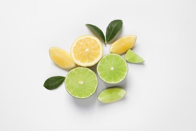 Fresh ripe lemons, limes and green leaves on white background, top view