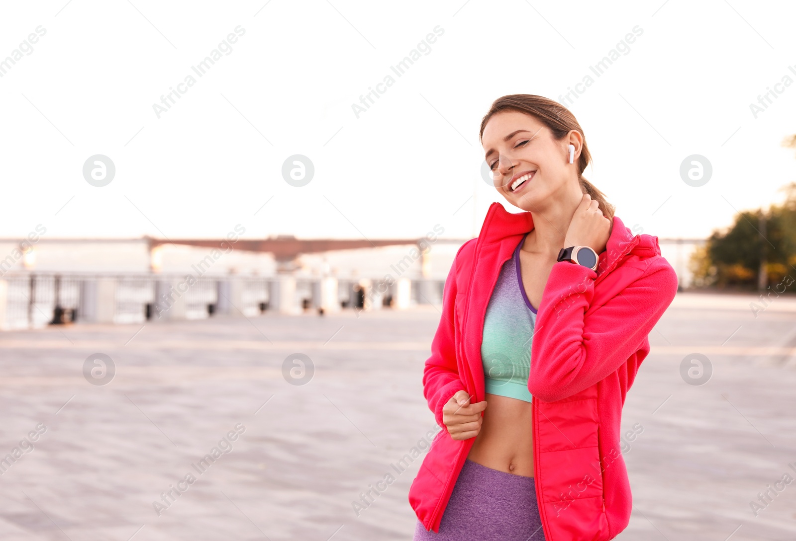 Photo of Young woman with wireless headphones listening to music outdoors. Space for text