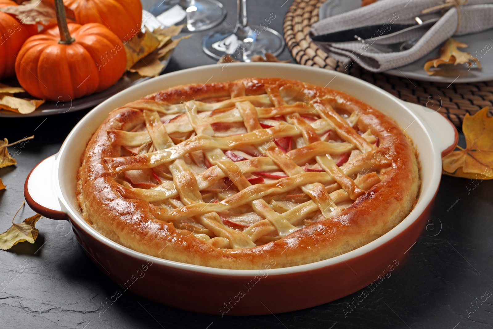 Photo of Delicious homemade apple pie and autumn decor on black table. Thanksgiving Day celebration