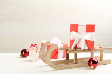 Photo of Beautiful Christmas composition with miniature sleigh on white table. Space for text