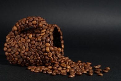 Cup made of coffee beans against black background