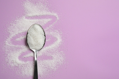 Granulated sugar and spoon on lilac background, flat lay. Space for text