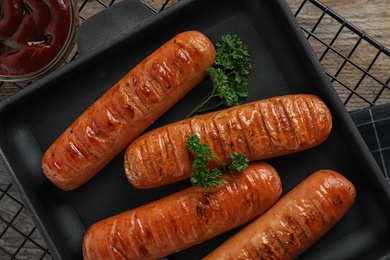 Photo of Flat lay composition with delicious grilled sausages on wooden table. Barbecue food