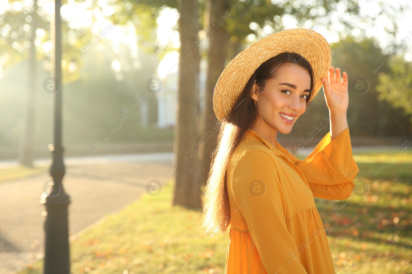 Photo of Beautiful young woman wearing stylish yellow dress and straw hat in park