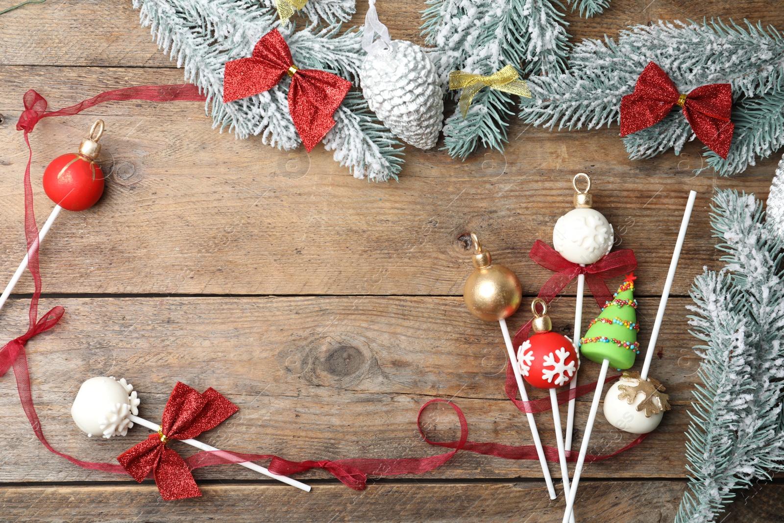 Photo of Frame of delicious Christmas themed cake pops on wooden table, flat lay. Space for text