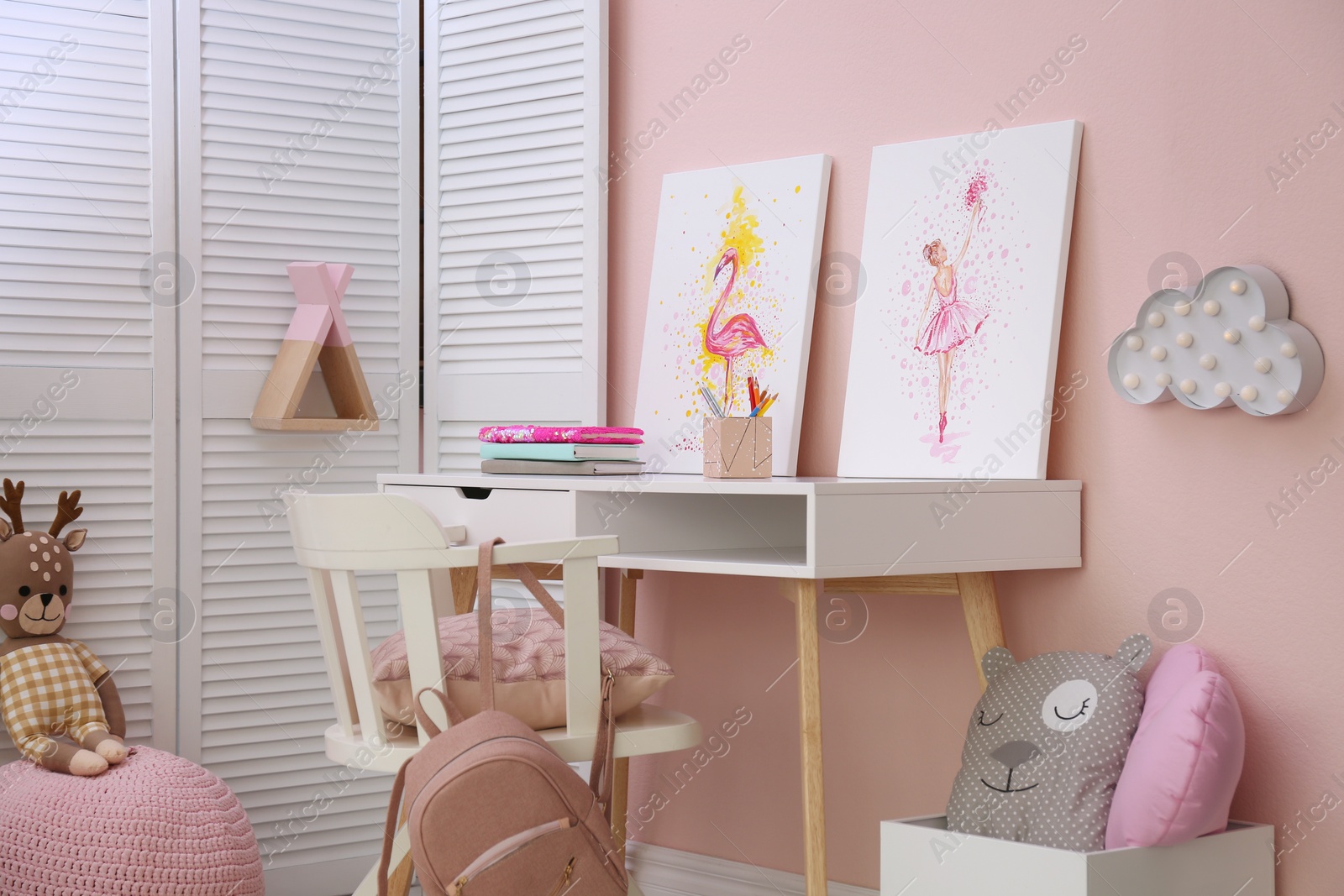 Photo of Stationery and pictures on white table in children's room. Interior design