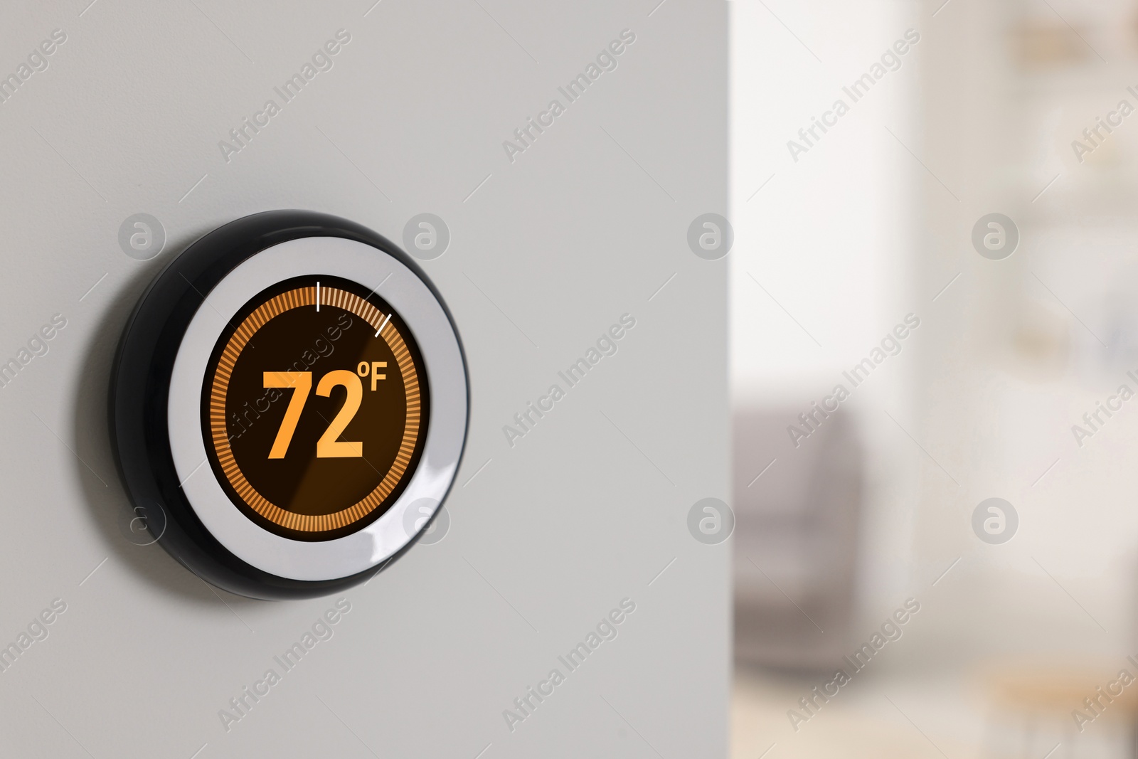 Image of Thermostat displaying temperature in Fahrenheit scale. Smart home device on white wall, space for text