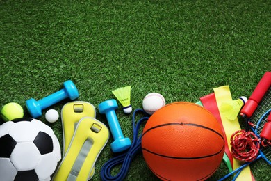 Photo of Set of different colorful sports equipment on green grass, flat lay. Space for text