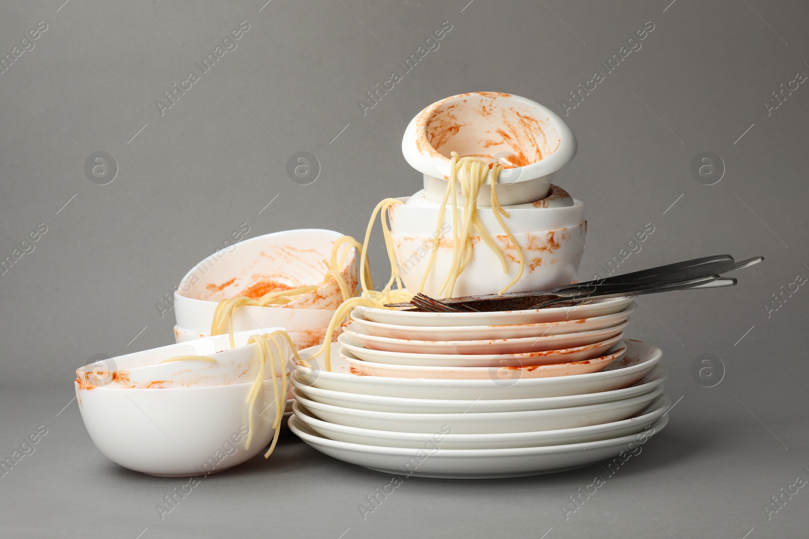 Photo of Set of dirty dishes with spaghetti leftovers on grey background