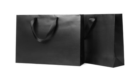 Paper shopping bags with ribbon handles on white background. Mockup for design