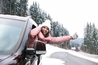 Photo of Young woman looking out of car window on road. Winter vacation