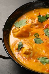 Tasty chicken curry with parsley and pepper on black textured table, closeup