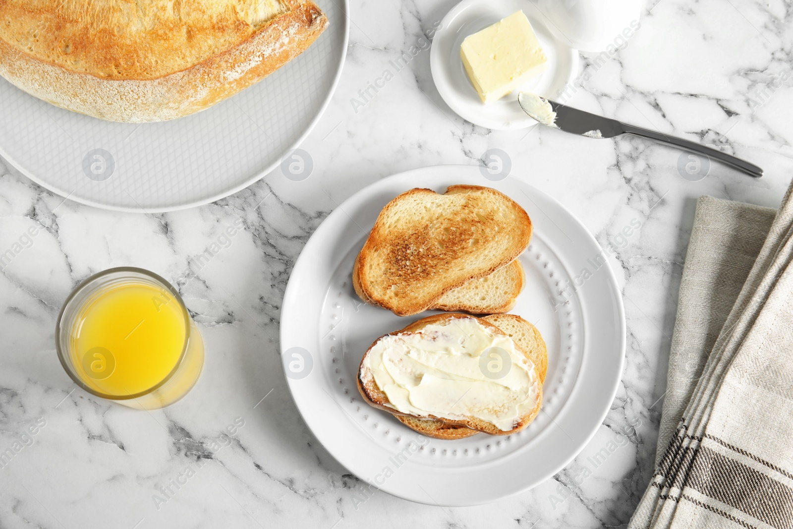 Photo of Tasty bread with butter served for breakfast on marble table, top view